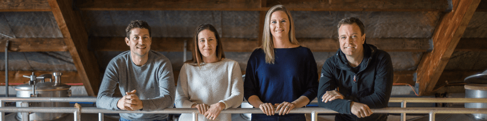 Four people smiling and leaning on railing