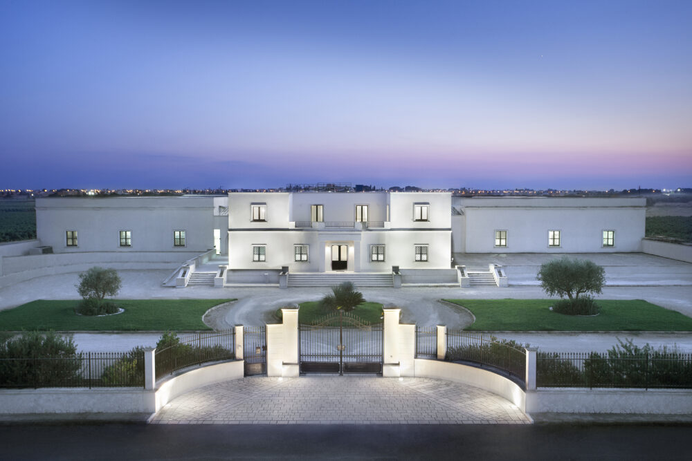 White mansion with gated driveway at dusk